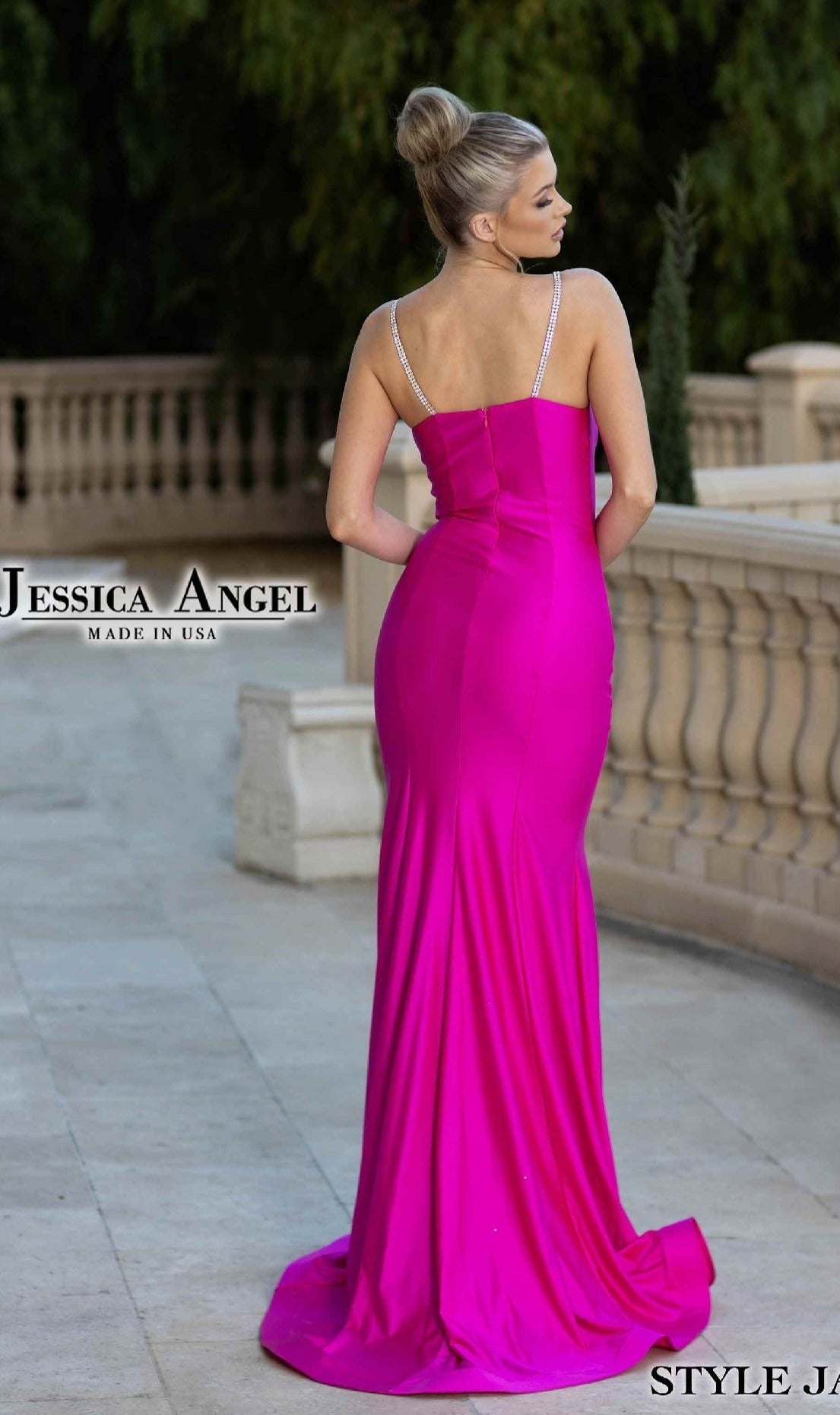 A woman stands outdoors on a stone patio, facing away from the camera, wearing the Beaded-Straps Long Prom Dress: Jessica Angel 798—a fitted, bright pink gown with thin beaded shoulder straps.